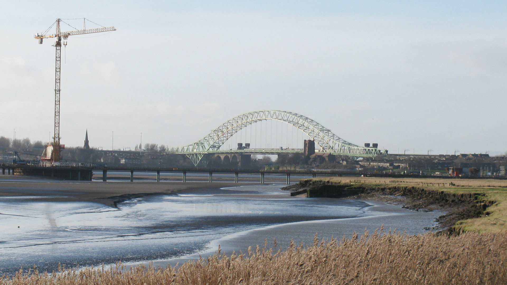 Views along the River Mersey show the Runcorn Road and Rail bridges beyond the Mersey Gateway Bridge being constructed